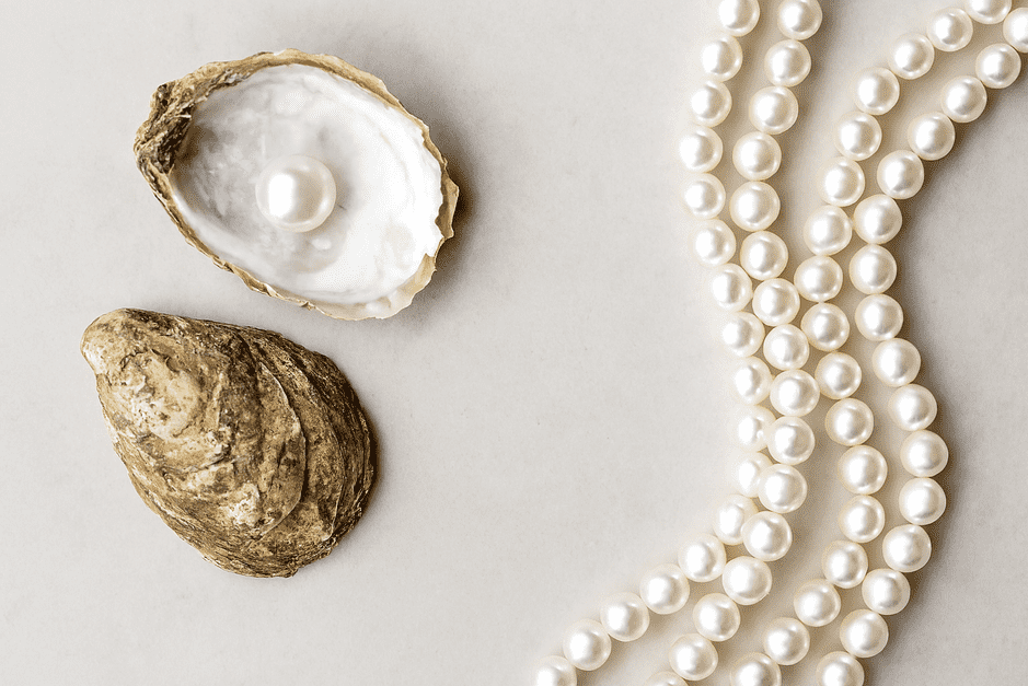 A side-by-side view of a natural pearl and a cultured pearl, illustrating their differing origins with a visual analogy of a wild berry versus a farmed berry.