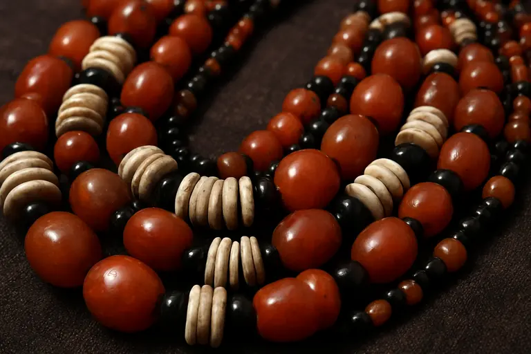 A traditional multi-strand Naga Bead Jewellery necklace with orange and black beads.