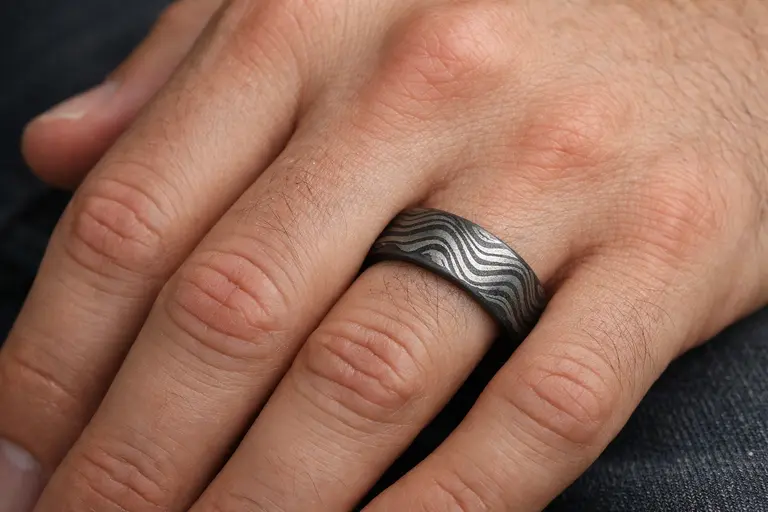 A man wearing a patterned Damascus Steel Jewelry wedding band.