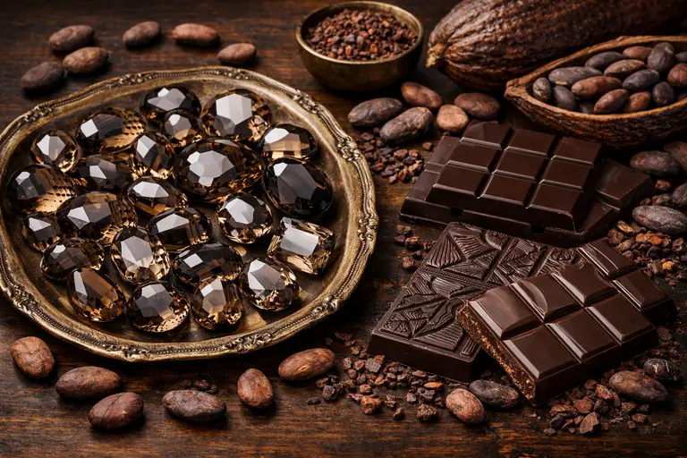 A tray of faceted brown gemstones alongside artisanal dark chocolate bars from Keralam.